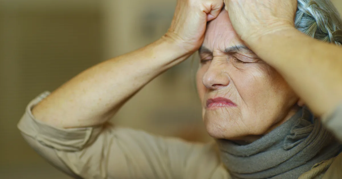 The image shows Early signs of Parkinson’s in women – elderly woman showing symptoms with stress and discomfort