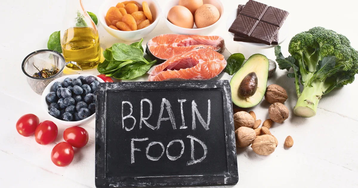 Brain health foods including salmon, avocado, nuts, berries, dark chocolate, eggs, and leafy greens arranged around a chalkboard labeled "Brain Food".