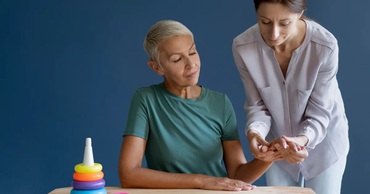A healthcare professional assisting an older woman with hand exercises, representing rehabilitation and care for managing neurological disorders.