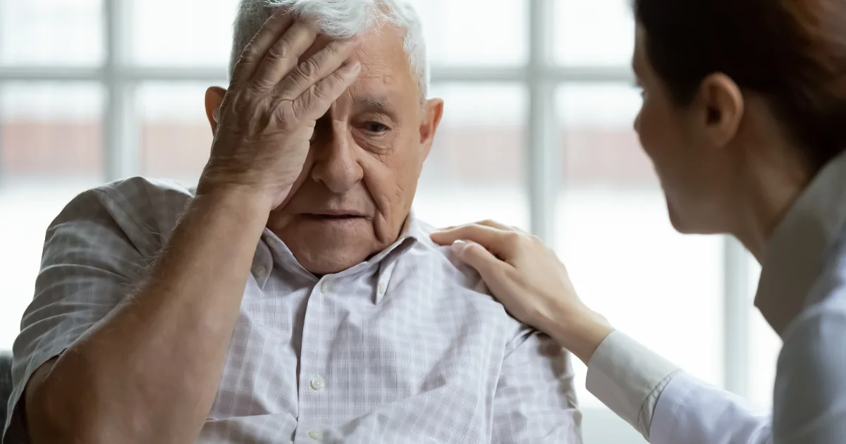 Healthcare professional comforting senior man, representing Parkinson's and stroke support.