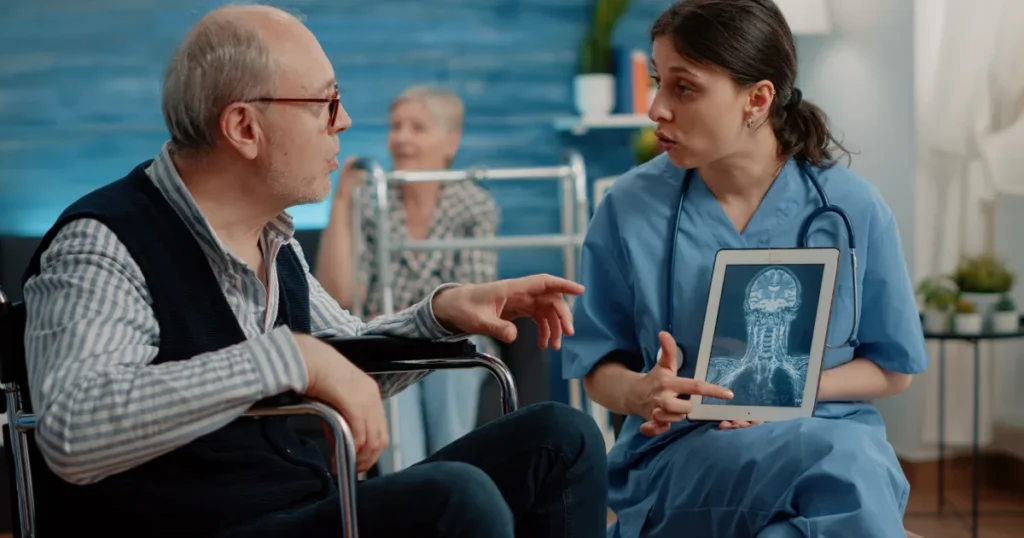 Neurologist discussing brain scan results with a Parkinson’s disease patient in a wheelchair, explaining symptoms and treatment options for “off” episodes.