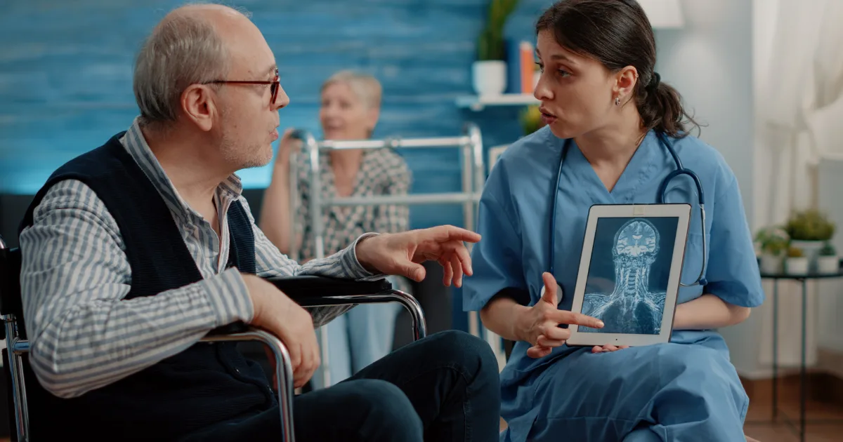 Neurologist discussing brain scan results with a Parkinson’s disease patient in a wheelchair, explaining symptoms and treatment options for “off” episodes.