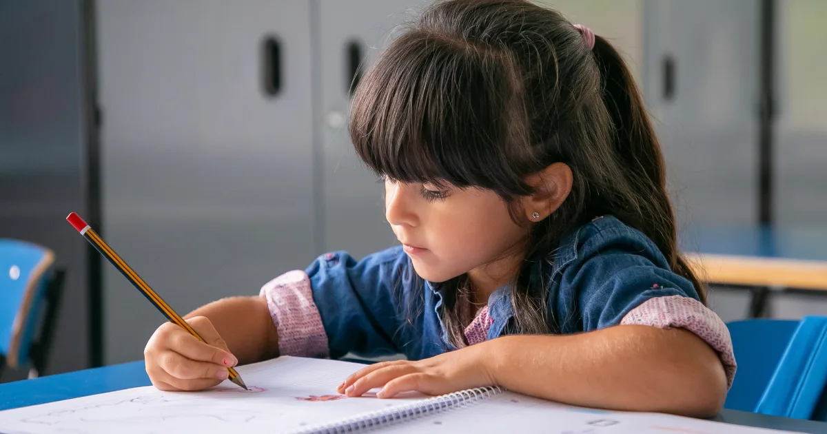 Young girl struggling to write due to tremors in childhood, highlighting early diagnosis importance.
