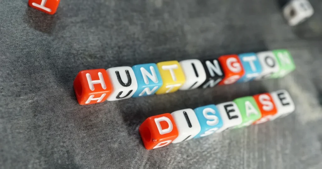 Colorful letter cubes spelling out Huntington’s disease on a textured background.