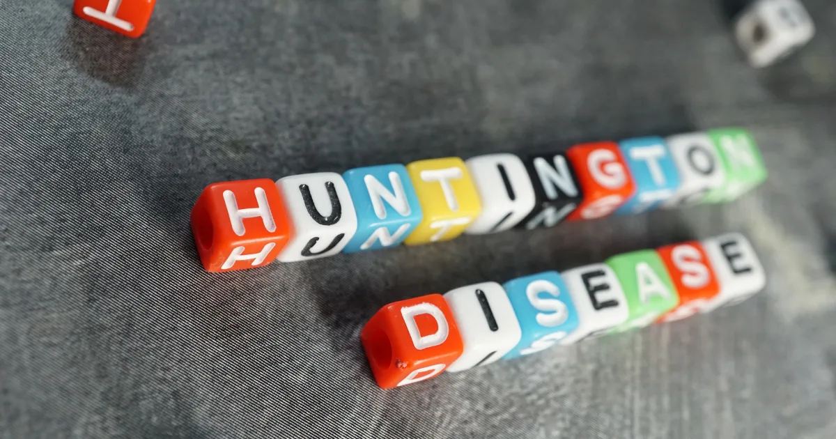 Colorful letter cubes spelling out Huntington’s disease on a textured background.