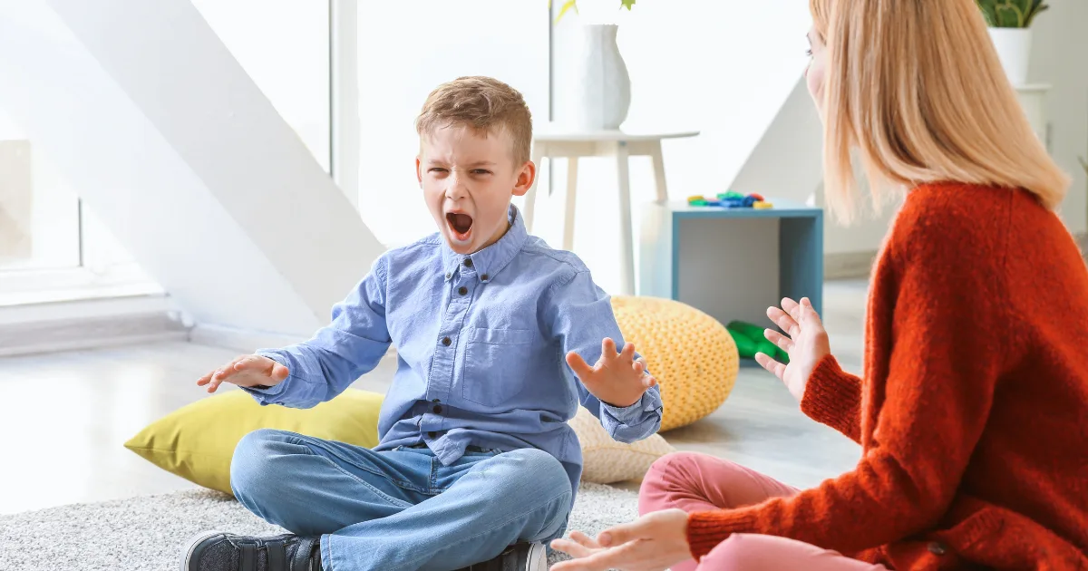 A young boy showing sudden, uncontrolled movements while sitting with a woman during a therapy session, representing tic disorders in children.