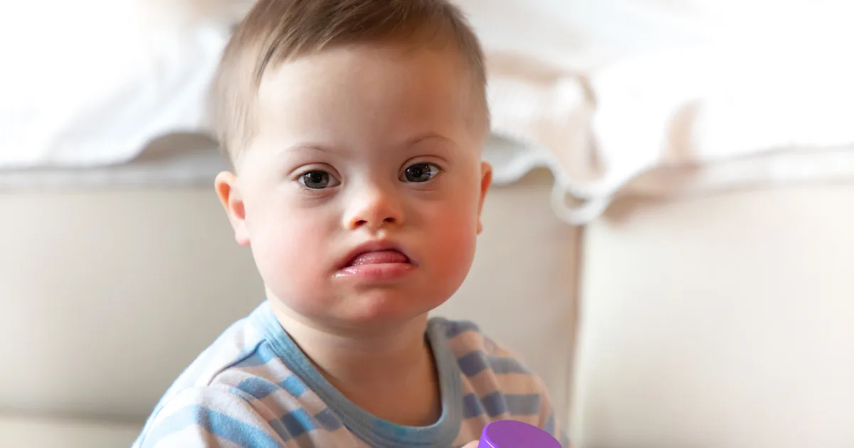 A young child sitting indoors, appearing thoughtful, representing a child experiencing tics and involuntary movements.
