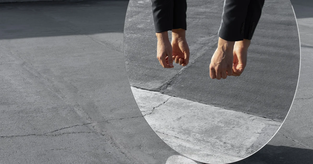 Reflection in mirror showing hands and arms above a concrete surface, illustrating mirror movements.