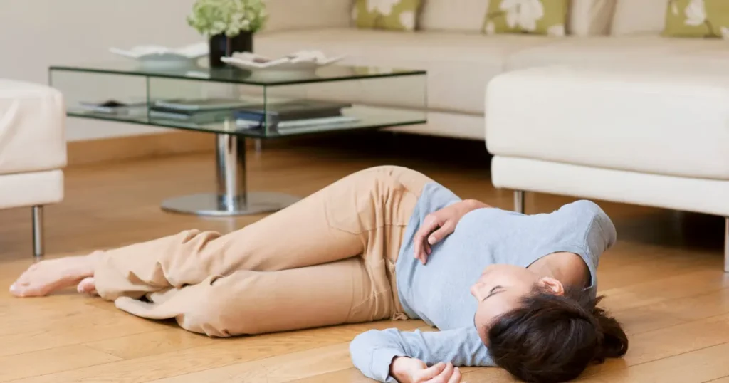 Woman lying unconscious on the floor, illustrating fainting as a possible symptom of MSA.