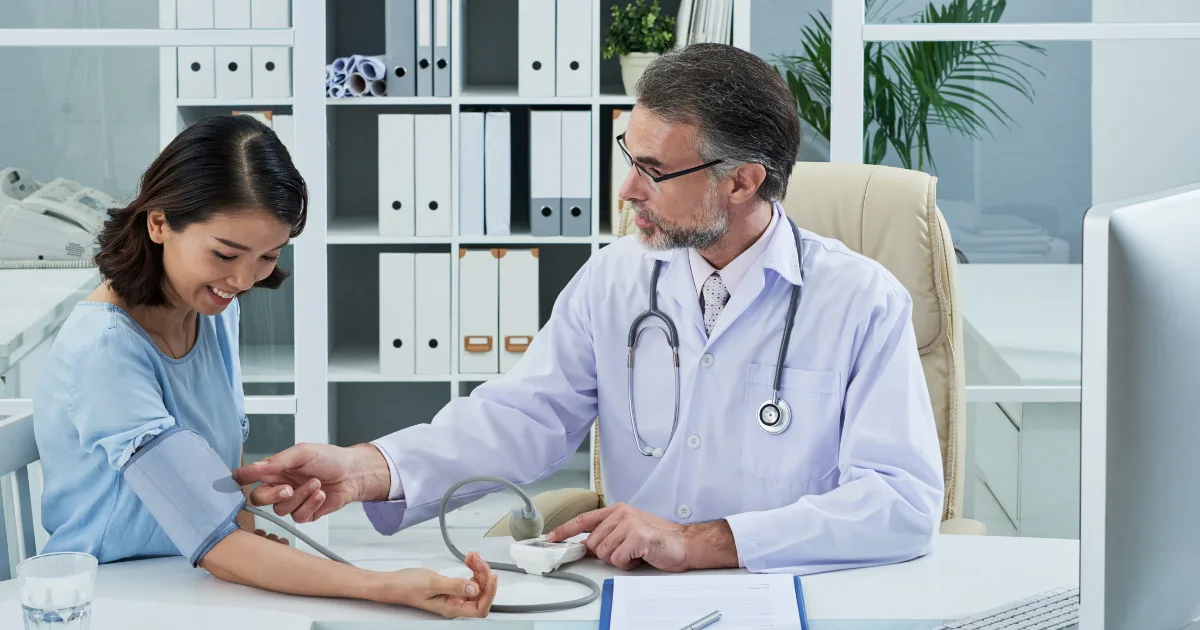 Doctor checking a patient’s blood pressure during a consultation, representing follow-up care and progress monitoring in Wilson’s Disease