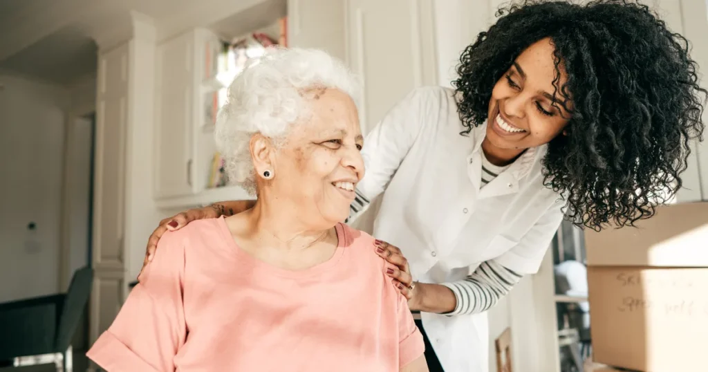 Elderly woman with PSP receiving supportive care and smiling with her caregiver, symbolizing improved quality of life and better PSP life expectancy.
