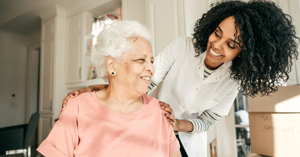 Elderly woman with PSP receiving supportive care and smiling with her caregiver, symbolizing improved quality of life and better PSP life expectancy.