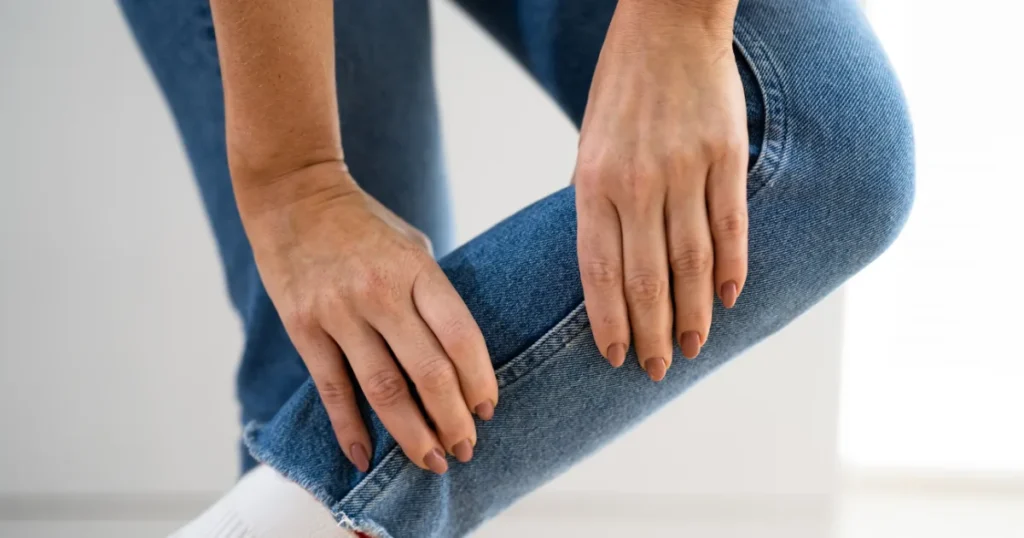 Person holding their leg due to discomfort, illustrating symptoms of Restless Legs Syndrome.