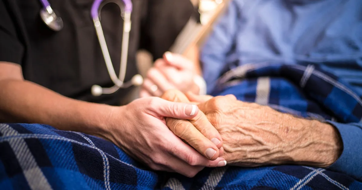 Healthcare provider holding an elderly patient’s hand, symbolizing support in managing slow progressing neurological conditions like CBD.