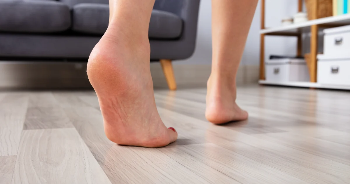 Bare feet walking indoors on wooden flooring, showing movement that may help improve RLS symptoms.