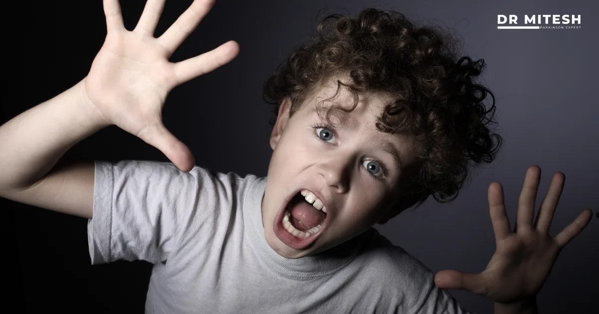 Child reacting suddenly with raised hands and open mouth, representing sudden jerks or shaking episodes seen in children.