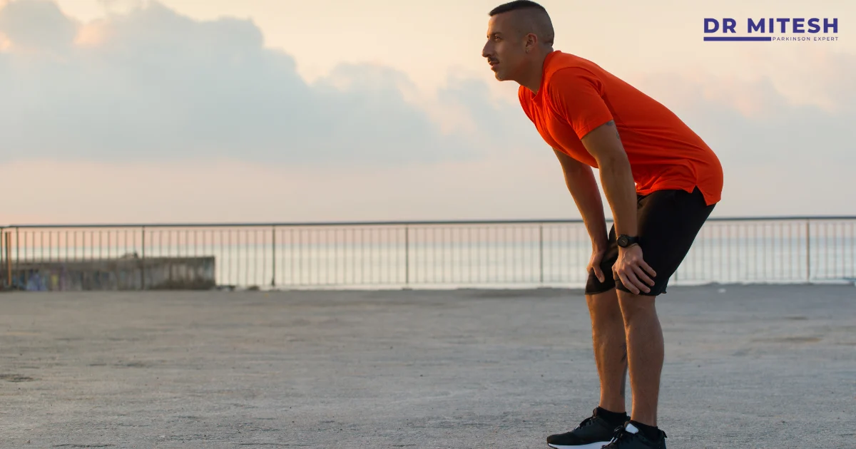 Man pausing after exercise and leaning forward with hands on knees, showing fatigue and movement symptoms affecting physical endurance.