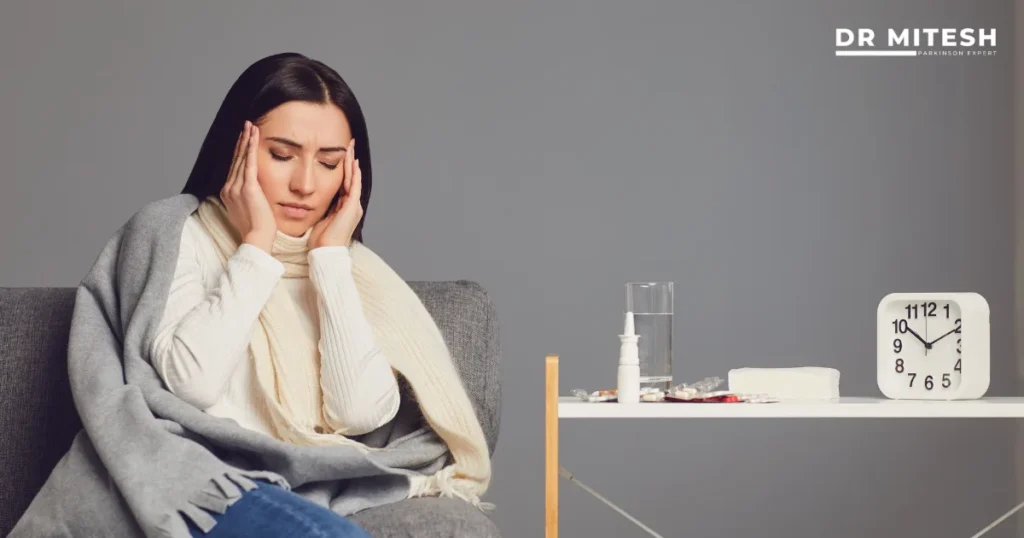 Woman holding her head while sitting on a sofa with medicines nearby, representing medicine side effect from long-term drug use.