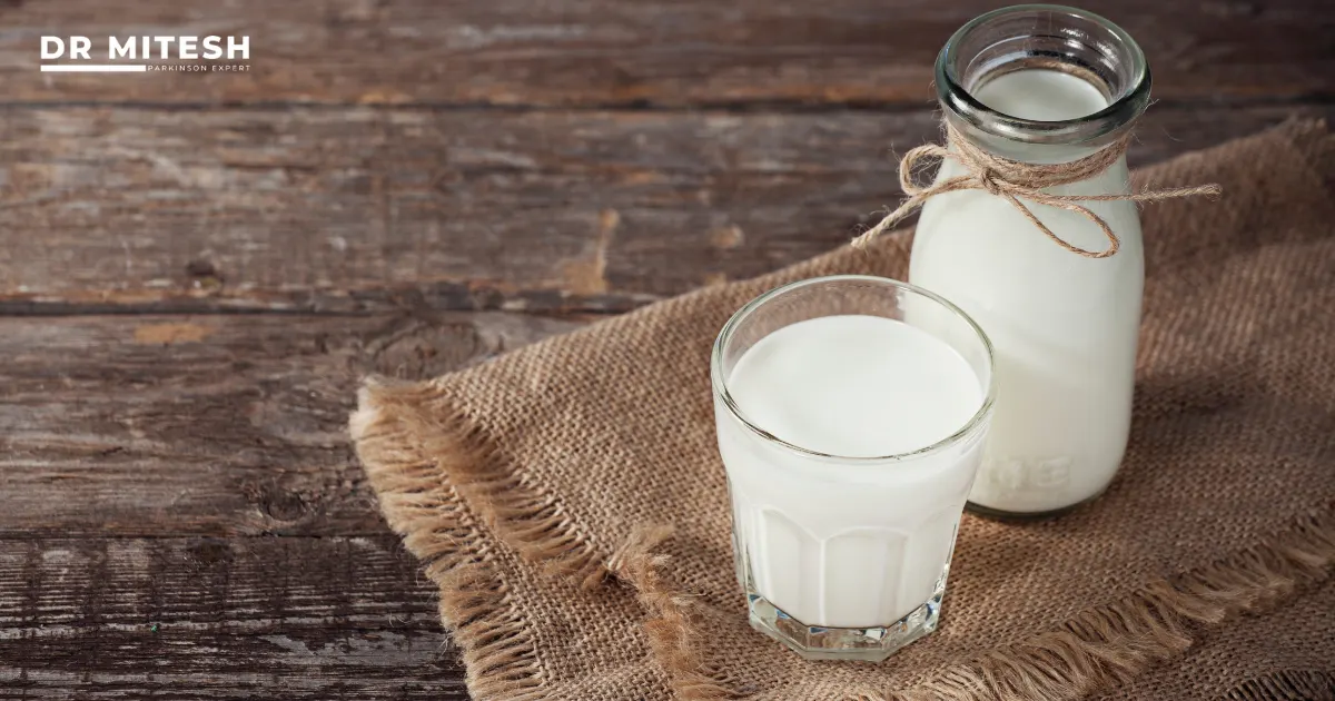 Glass and bottle of Milk placed on a rustic table, representing daily Milk consumption and its possible connection with Parkinson’s disease.