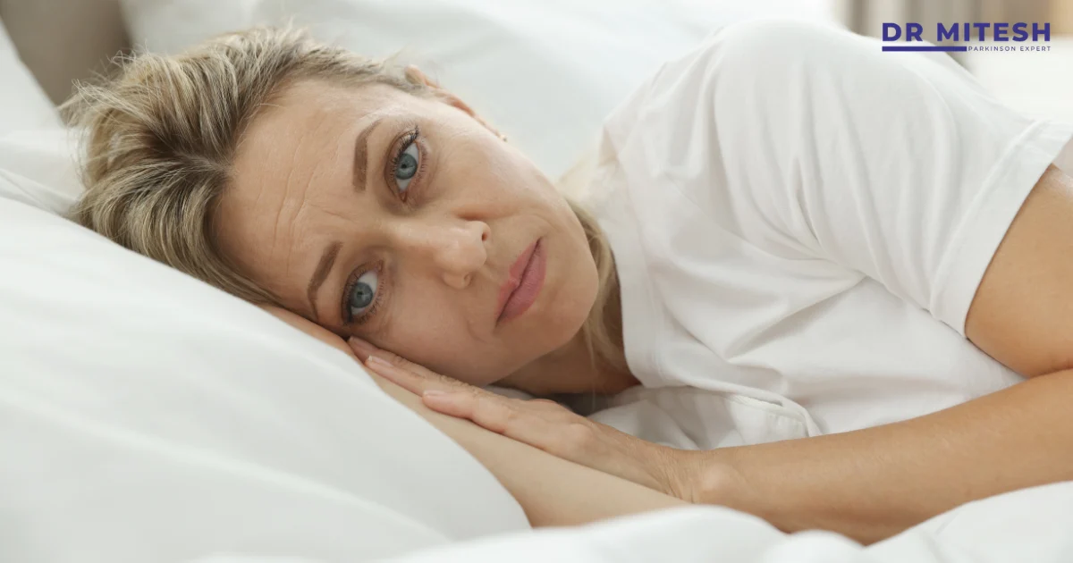 Woman lying awake in bed showing sleep problems that can occur in Parkinson’s disease