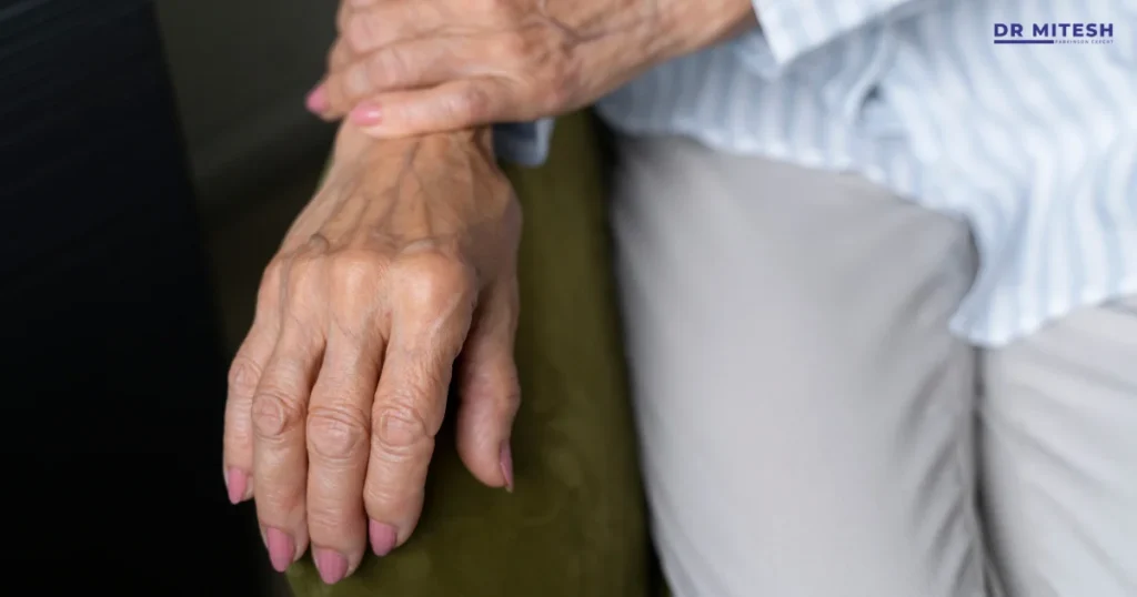 Elderly person experiencing hand tremors while holding wrist, possible Parkinson’s or essential tremor symptom