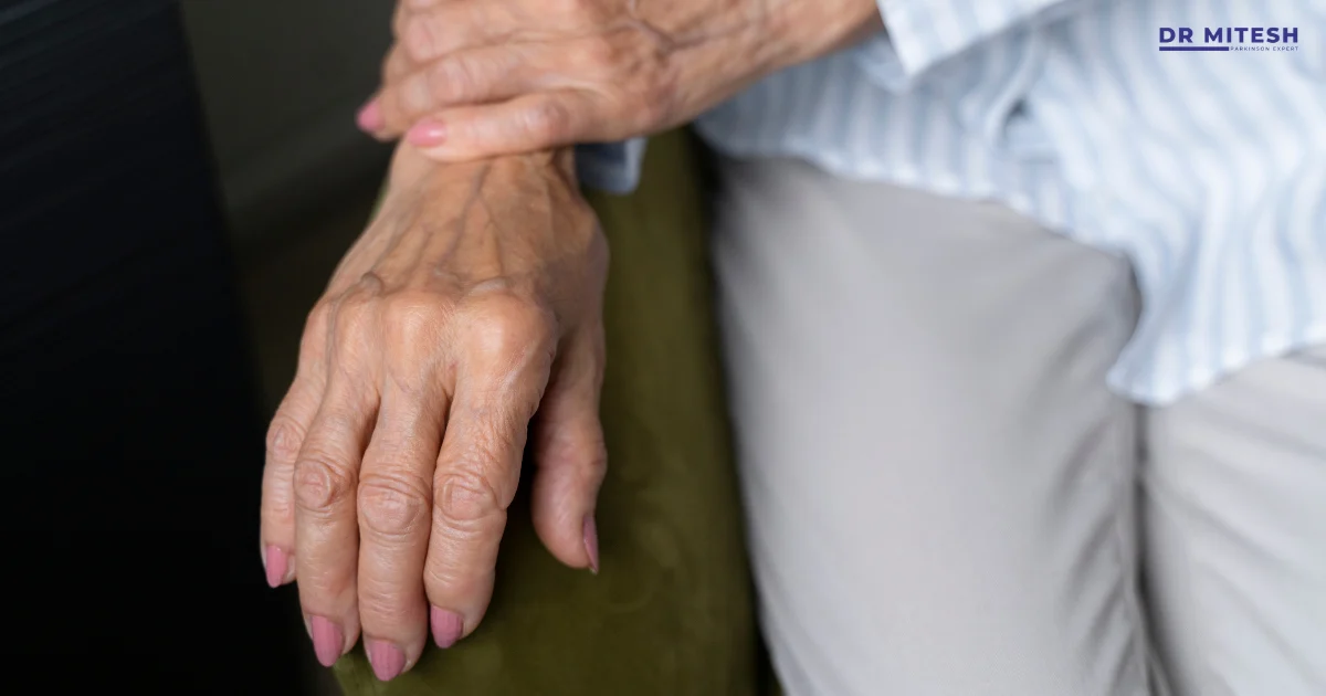 Elderly person experiencing hand tremors while holding wrist, possible Parkinson’s or essential tremor symptom